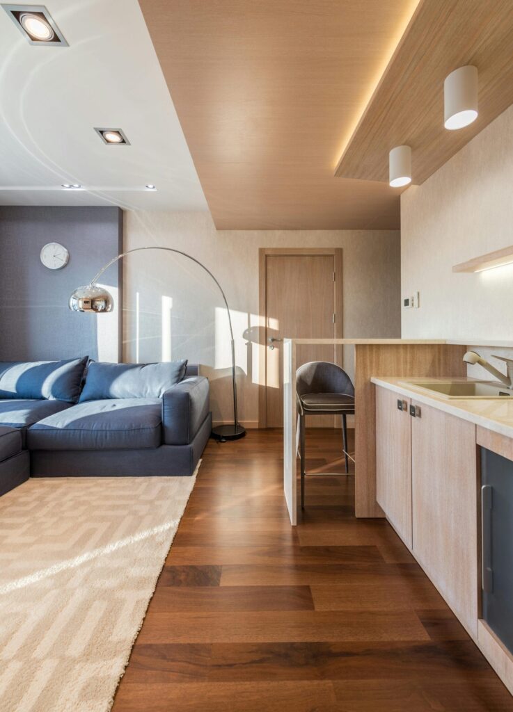 Spacious modern living room featuring a blue sectional sofa and an open kitchen area.