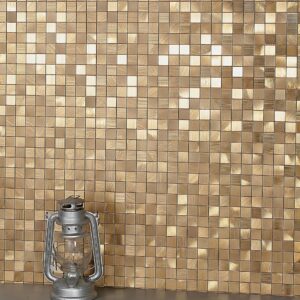 Close-up of a gold mosaic tile wall featuring a vintage lantern in the foreground.